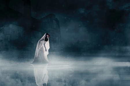 Halloween horror concept. Horrible female ghost wearing bloody bride gown while walking near spooky...