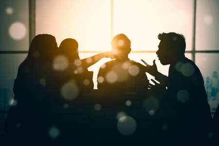 Silhouette of two angry people accusing each other while meeting business in the office with sunlight backgroundの写真素材