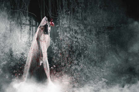 Halloween horror concept. Side view of horrible female bride with wounded face walking in the the...