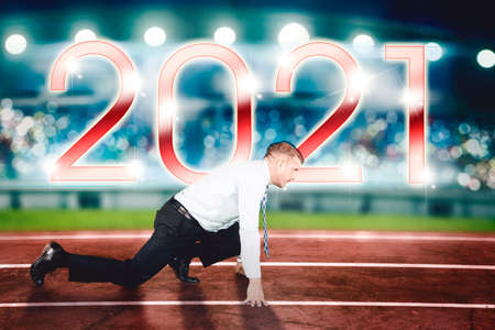 Side view of Caucasian businessman ready to run on the track lines with 2021 numbers background
