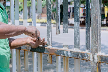 Close up of worker hands using  knife to removing old paint.