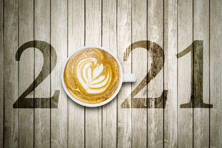 Happy new year concept. Top view of latte coffee art with number 2021 on the wooden table