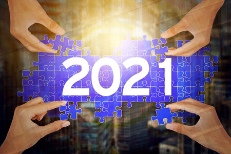 Double exposure of four young people hands arranging puzzle with number 2021 and modern city...