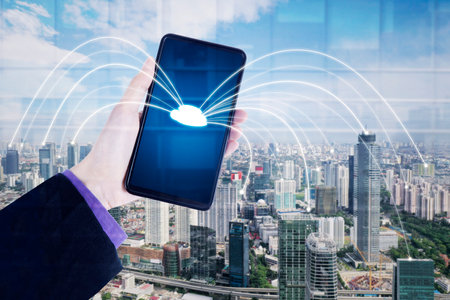 Cloud storage concept. Close up of young businessman hand holding a mobile phone with cloud symbol and connection network in smart city backgroundの写真素材