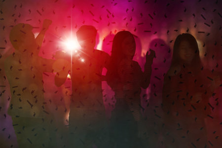 Silhouette of crowd people cheering and dancing under falling confetti with red lights background