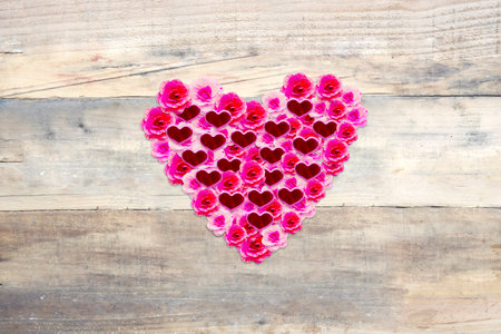 Close up of pink flowers with knick knacks shaped heart symbol on the wooden table. Valentines day conceptの写真素材