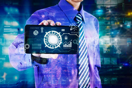 Close up of businessman hand showing button virtual on cellphone screen while standing with virtual screen backgroundの写真素材