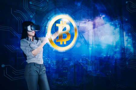 Double exposure of businesswoman using VR headset while touching bitcoin button on virtual screen