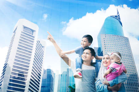 Low angle view of a happy Muslim family enjoying leisure time together while looking at modern city...