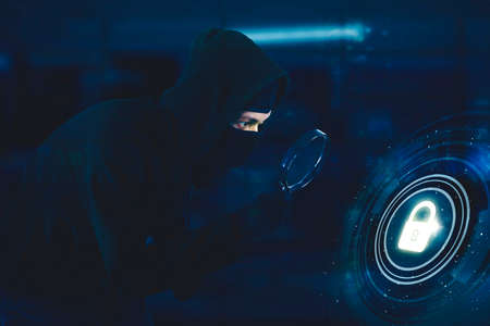 Hooded hacker using a magnifier to looking at security padlock virtual while hacking user...