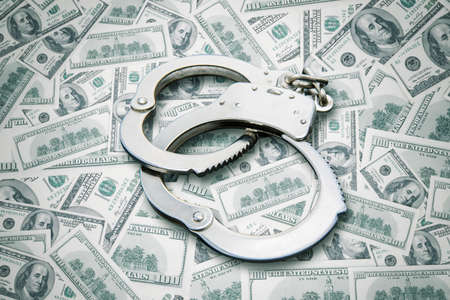 Close up of handcuffs over stack of dollar banknotes. Corruption crime conceptの写真素材