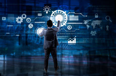 Back view of male manager pressing a button on virtual screen while standing with double exposure of...
