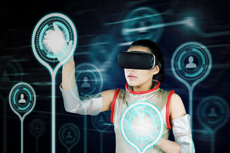 Futuristic woman pressing social network connection on virtual screen while standing in the cyberspaceの写真素材