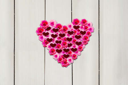 Top view of pink flowers with knick knacks shaped heart symbol on the wooden table. Valentines day...