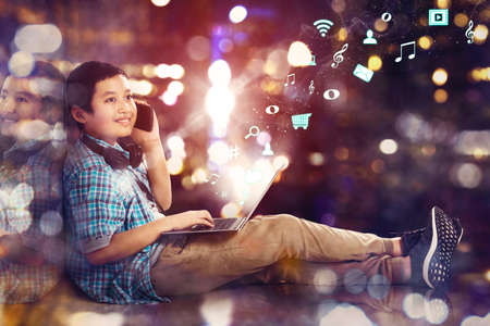 Double exposure of preteen schoolboy make a call phone while using a laptop with notification social...
