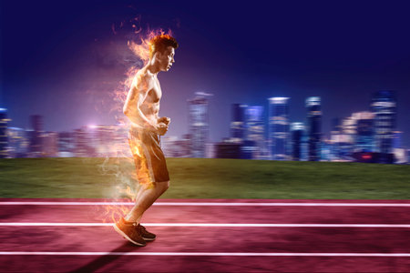 Side view of male athlete running fast as fire flame on the track with night city backgroundの写真素材