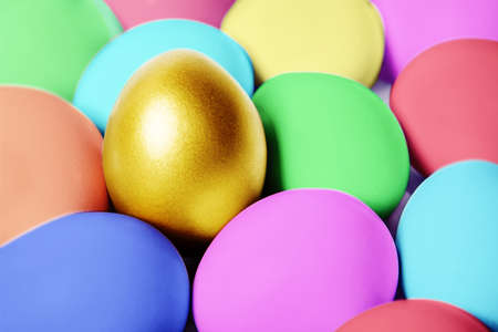 Close up of a gold egg on hiding in between colorful easter eggs