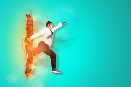 Young businessman jumping obstacles through torn paper with copy spaceの写真素材