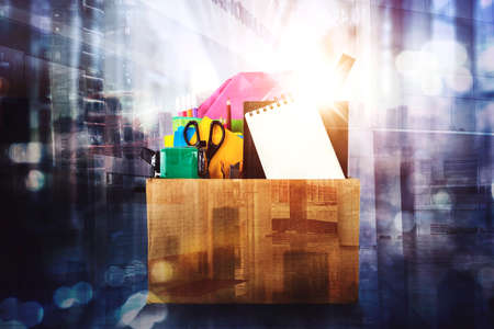 Double exposure of school supplies in cardboard box with skyscrapers and blurred sparkling lights...
