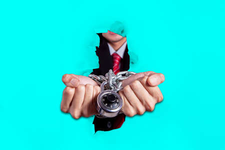 Close up of businessman hands handcuffed by padlock while breaking through paper wallの写真素材