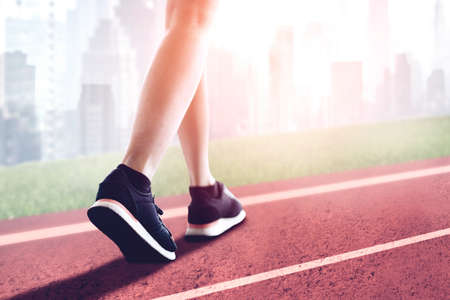 Close up of young woman foot running and exercising on the track with cityscape backgroundの写真素材
