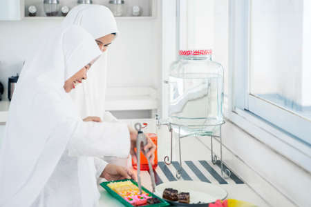 Muslim woman and her mother preparing snack and drink in the kitchen during Eid Mubarak. Shot at homeの写真素材