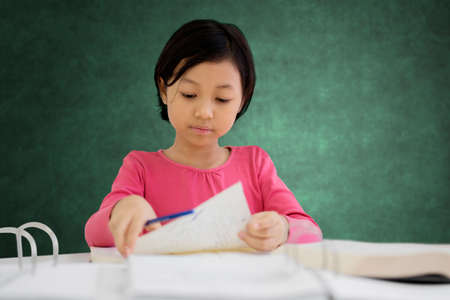 Image of adorable schoolgirl holds paper before doing assignment school while sitting in the classroomの写真素材