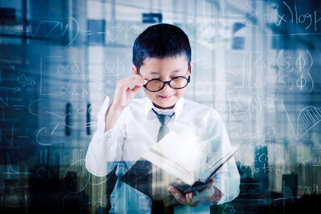 Double exposure of  schoolboy reading a textbook while standing with doodles backgroundの写真素材