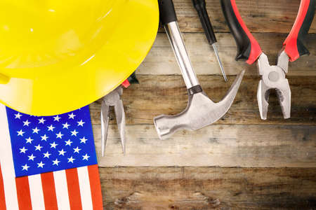 Top view of construction tools, helmet and American flag with copy space on wooden table background