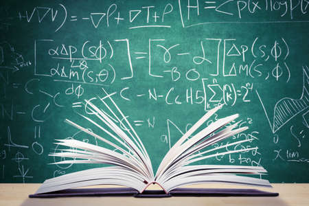 Close up of open book above the table with doodles background in the classroomの写真素材