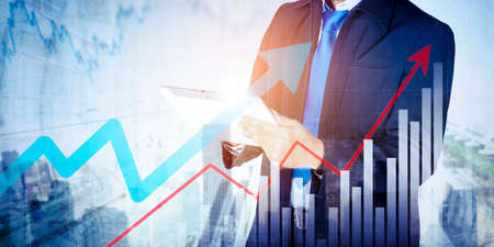 Double exposure of young businessman hands using a digital tablet while standing with upward arrows...