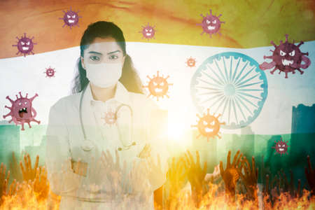 Double exposure of female doctor wearing face mask while standing with India flag and Coronavirus germs backgroundの写真素材