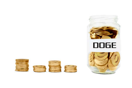 Cryptocurrency investment concept. Close up of glass jar full of golden coins with Doge word. Isolated on white backgroundの写真素材