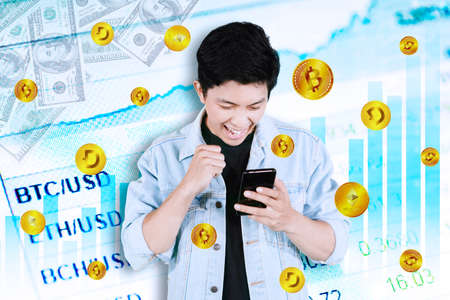 Excited young man using a mobile phone while getting cryptocurrency coins with exchange rate price...