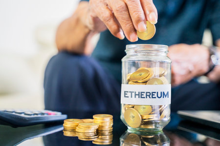 Cryptocurrency investment concept. Close up of senior man hand saving Ethereum coins in a glass jar with Etherum word.の写真素材