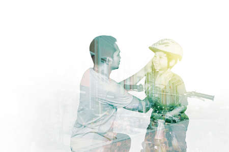 Double exposure of young man fastens a helmet to his son while ready to riding on the bicycle with...
