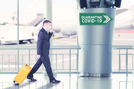 Sick businessman wearing face mask while carrying a luggage and walking toward covid-19 quarantine...