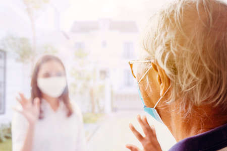 Sick father communicating with his daughter through a window while getting self isolation at homeの写真素材