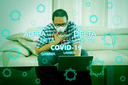 Young man getting infected covid-19 mutation variant while working from home with laptop during self isolation at homeの写真素材