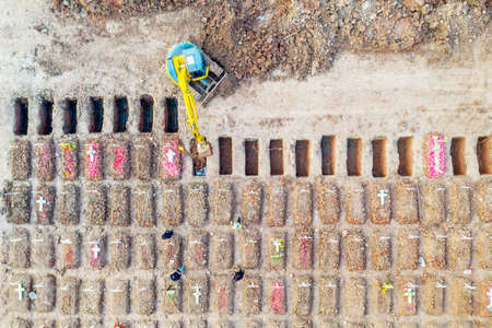 JAKARTA - Indonesia. July 26, 2021: Aerial view of yellow excavator digs grave pits to the burial Covid-19 victims at Rorotan graveyard in North Jakarta, Indonesiaのeditorial素材