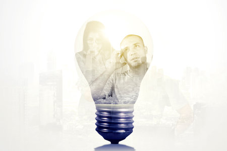 Close up of light bulb with double exposure of two pensive people on cityscape backgroundの写真素材