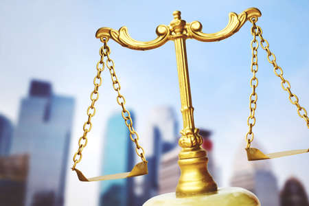 Close up of gold scales of justice and law symbol with blue sky backgroundの写真素材