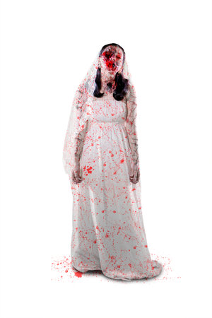 Halloween horror concept. Full length of terrifying female ghost wearing bride gown while standing in the studio. Isolated on white backgroundの写真素材