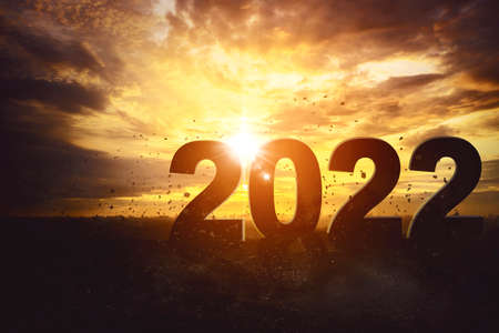 Silhouette of 2022 numbers with flying gravels in dramatic sky background at sunset timeの写真素材