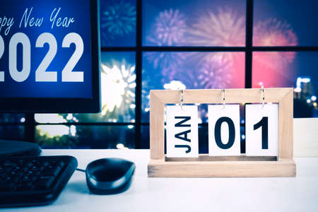 Close up of computer desktop showing Happy New Year 2022 text with calendar of January with date of 01 on the office desk near windowの写真素材