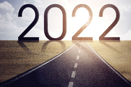 Image of an empty road toward bright 2022 numbers at morning time. Happy new year concept