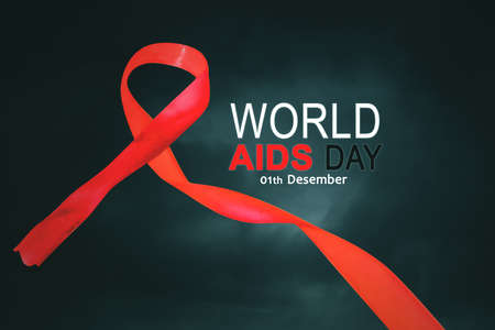 Close up of red ribbon with World Aids Day text in dark background
