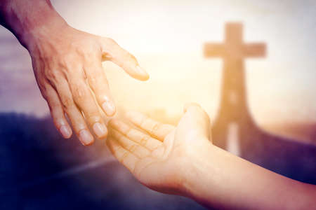God salvation concept. Close up of God's hand reaching a human hand with Cross symbol on end of roadの写真素材