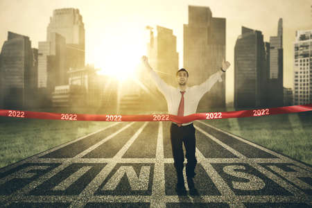 Arabian businessman expressing happy while finishing race and crossing the finish line with 2022...