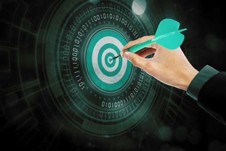 Close up of businessman hand aiming to the target of dartboard with code binary in cyberspaceの写真素材